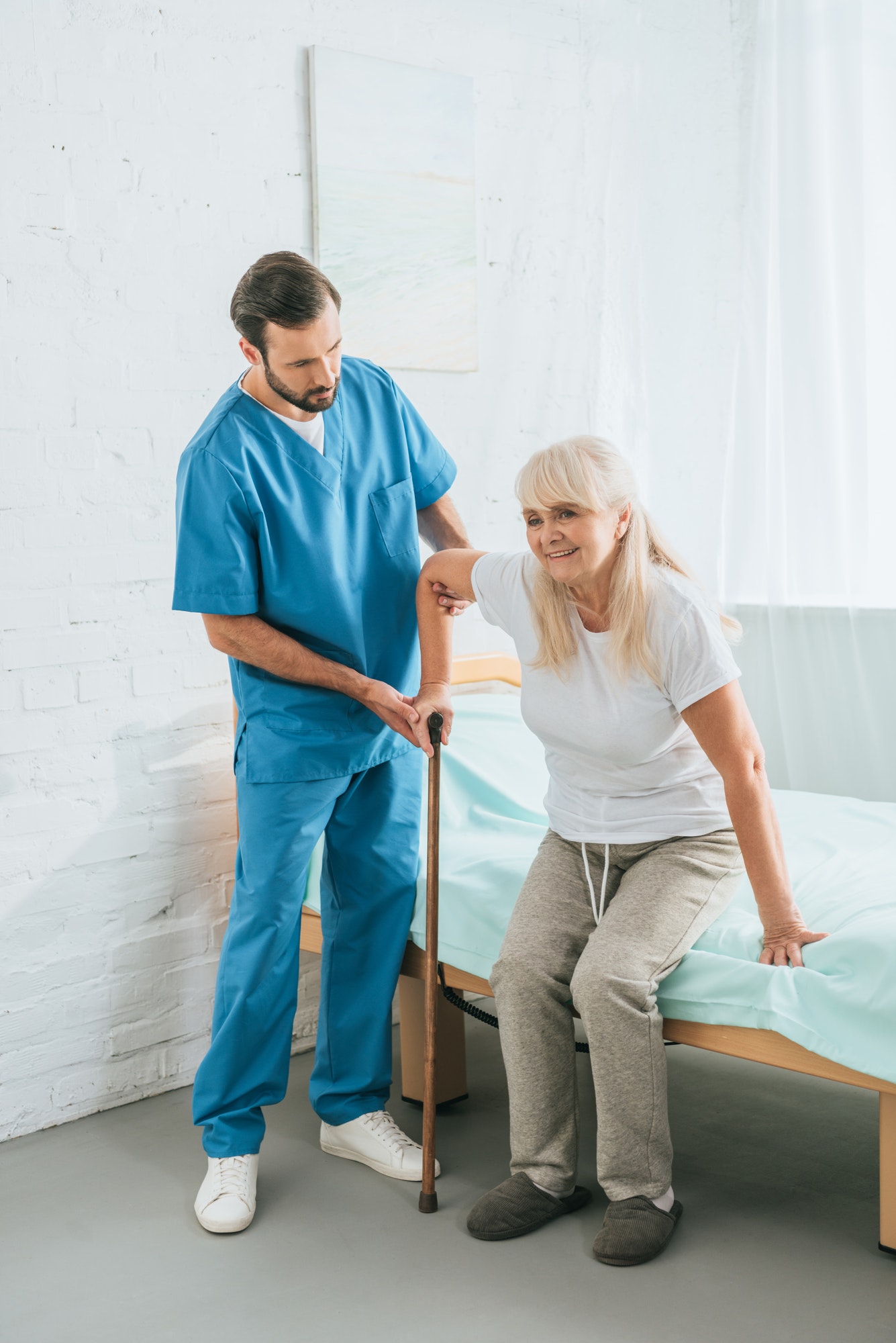 Pfleger hilft Seniorin mit Gehstock